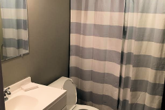 bathroom with blue and white striped shower curtain, white toilet and sink
