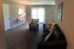 apartment living room with a blue couch, black and white love seat, and rose colored carpet