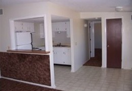 apartment kitchen and dining area with tan walls and white black splash, white appliances, and cupboards