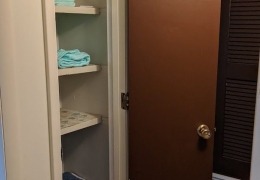 apartment linen closet. the closet is thin and tall with 5 shelves