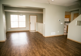 entry room of an apartment with wood floors and grey walls there is light flowing in from the windows and it is empty of furniture and ready for rent