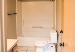 apartment bathroom with grey walls, white toilet, and white tile shower and bath combo there is no shower curtain as the apartment is ready for rent