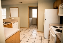 apartment kitchen and laundry room with grey walls, white appliances, light brown cupboards, and white tile floor it is empty and ready to rent