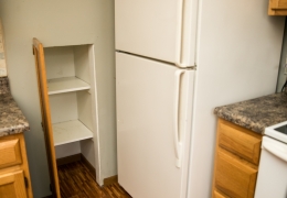 apartment kitchen with grey walls white refrigerator light brown cupboards grey granite and wood floor