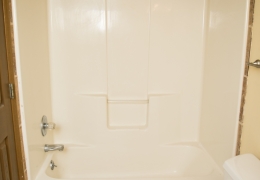 apartment bathroom with grey walls, white toilet, and white tile shower and bath combo there is no shower