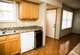 apartment kitchen with grey walls white appliances light brown cupboards and wood floor there is light flowing in from the windows and it is empty and ready for rent