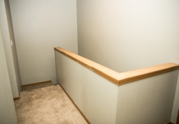 second floor stairwell landing with light grey carpet and walls and wood trim