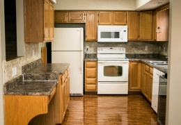 apartment kitchen with grey walls white appliances light brown cupboards grey granite and wood floor