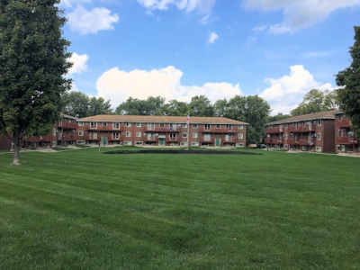 multi story apartment building with large green lawn in front and blue sky behind